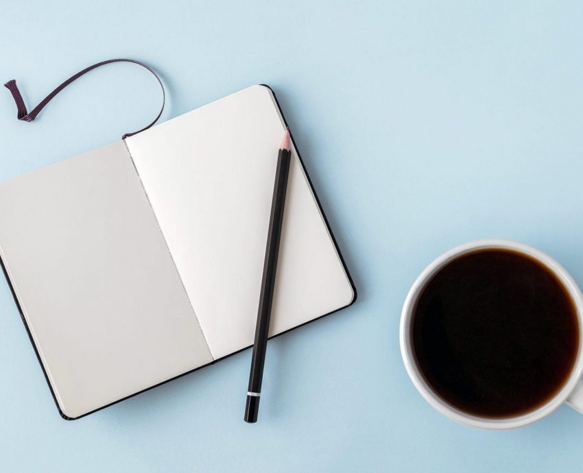 Office blue table with blank notepad, pencil, glasses and coffee cup. Copy space for text. Flat lay. Top view